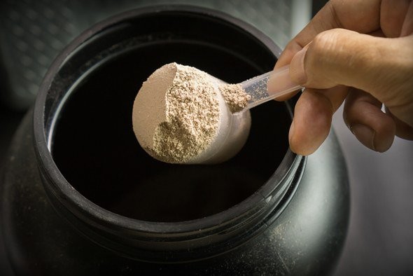 protein-powder-being-scooped-out-of-large-container